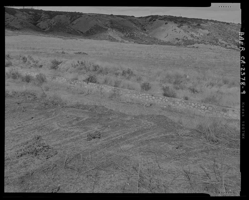 Contextual view of southern end of channel, showing east rock wall, west wall not visible; looking north. - Gilman Canyon Storm Drain, Banning Bench to North 8th & West Nicolet Streets, Banning, Riverside County, CA