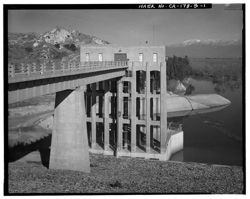  LOOKING NORTH AT SOUTH FRONT OF CONTROL HOUSE. ALSO SHOWN ARE THE CONTROL TOWER, THE SERVICE BRIDGE, AND THE SERVICE BRIDGE PIER. SNOW COVERED MT. BALDY IS VISIBLE IN THE DISTANCE. - Prado Dam, Outlet Works, Santa Ana River near junction of State Highways 71 & 91, Corona, Riverside County, CA