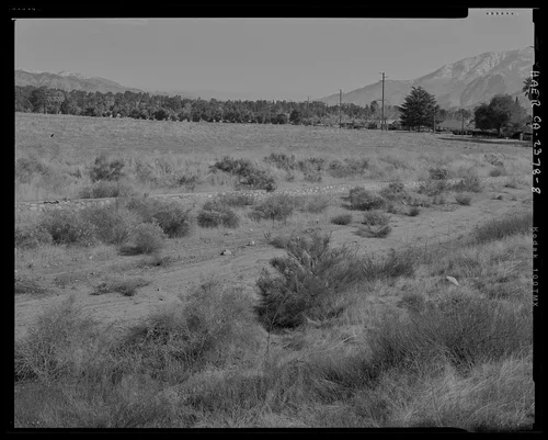 Contextual view of middle section of channel showing eastern rock wall of channel; west wall not visible; looking east. - Gilman Canyon Storm Drain, Banning Bench to North 8th & West Nicolet Streets, Banning, Riverside County, CA