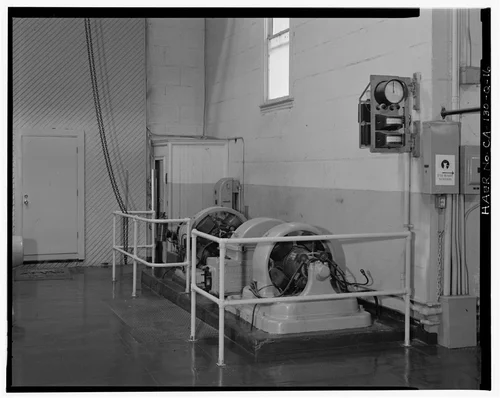  EXCITERS, AND SYNCHROSCOPE GAUGE ON WALL.  ACTIVE ELECTRIC EXCITER AT REAR; UNUSED WATER-DRIVEN EXCITER IN FOREGROUND.  VIEW TO SOUTH-SOUTHWEST. - Santa Ana River Hydroelectric System, SAR-2 Powerhouse, Redlands, San Bernardino County, CA