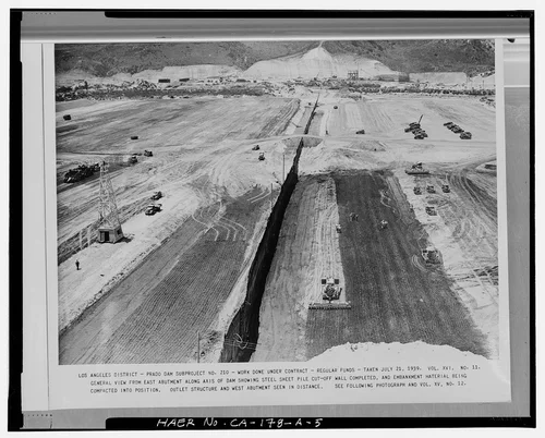  GENERAL VIEW FROM EAST ABUTMENT ALONG AXIS OF DAM SHOWING STEEL SHEET PILE CUTOFF WALL COMPLETED, AND EMBANKMENT MATERIAL BEING COMPACTED INTO POSITION. Volume XVI, No. 11, July 21, 1939. - Prado Dam, Embankment, Santa Ana River near junction of State Highways 71 & 91, Corona, Riverside County, CA