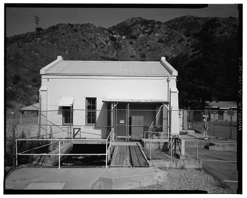  WEST ELEVATION, SHOWING TAILRACE AND SLIDING DOOR UNDER SHED ROOF. ADMINISTRATIVE OFFICE IS IN BACKGROUND AT RIGHT. VIEW TO EAST-NORTHEAST. - Santa Ana River Hydroelectric System, SAR-3 Powerhouse, Redlands, San Bernardino County, CA