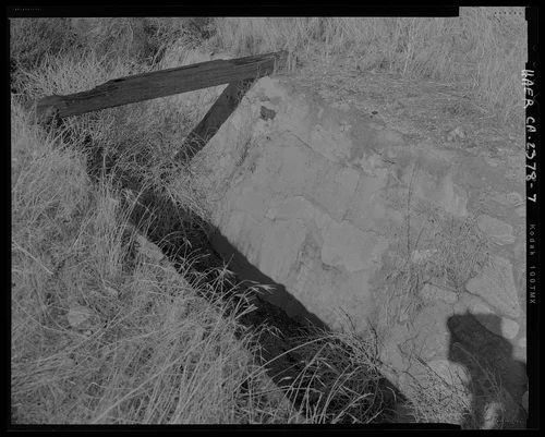 Detail view of middle section of channel showing cement modification repair on east face of channel, top edge of west side in foreground, wooden plank across channel in background; looking north-northwest. - Gilman Canyon Storm Drain, Banning Bench to North 8th & West Nicolet Streets, Banning, Riverside County, CA