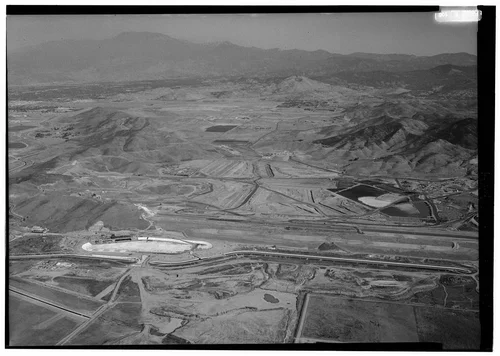  WEST DAM, LOOKING EAST. TIP OF OUTLET STRUCTURE CAN BE SEEN ON HILL ABOVE PUMP PLANT. - Eastside Reservoir, Diamond & Domenigoni Valleys, southwest of Hemet, Hemet, Riverside County, CA