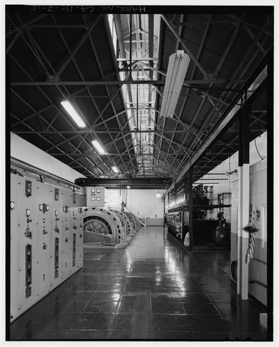  INTERIOR OVERVIEW TO SOUTHEAST. ACTIVE CONTROL PANEL AND GENERATORS AT LEFT, HISTORIC CONTROL PANEL AT RIGHT. - Santa Ana River Hydroelectric System, SAR-1 Powerhouse, Redlands, San Bernardino County, CA