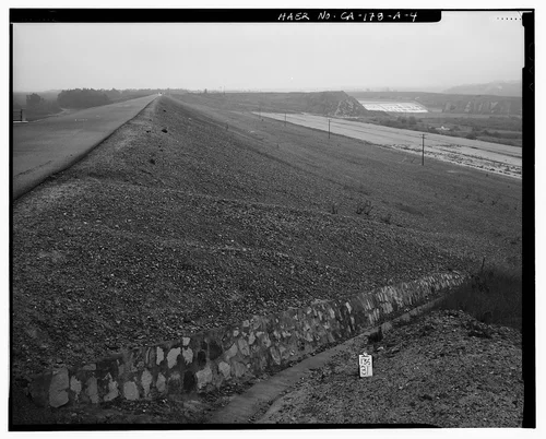  OVERVIEW TO EAST, FROM WEST END OF EARTHEN EMBANKMENT, SHOWING DOWNSTREAM FACE OF DAM, AND SPILLWAY FACE IN DISTANCE AT UPPER RIGHT. - Prado Dam, Embankment, Santa Ana River near junction of State Highways 71 & 91, Corona, Riverside County, CA