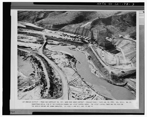  DOWNSTREAM AERIAL VIEW OF THE DIVERSION CHANNEL AND CONTROL WORKS. THE OUTLET CONTROL TOWER AND THE PIER FOR THE SERVICE BRIDGE ARE SHOWN COMPLETED.... Volume XVIII, No. 11, January 18, 1940. - Prado Dam, Santa Ana River near junction of State Highways 71 & 91, Corona, Riverside County, CA