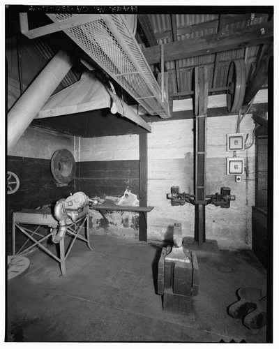  FORGE, ANVIL, PEDESTAL GRINDER, AND BELT DRIVES. NOTE WATERWHEEL NEEDLE VALVE CASTING HANGING ON THE WALL ABOVE THE FORGE. VIEW TO NORTH. - Santa Ana River Hydroelectric System, SAR-1 Machine Shop, Redlands, San Bernardino County, CA