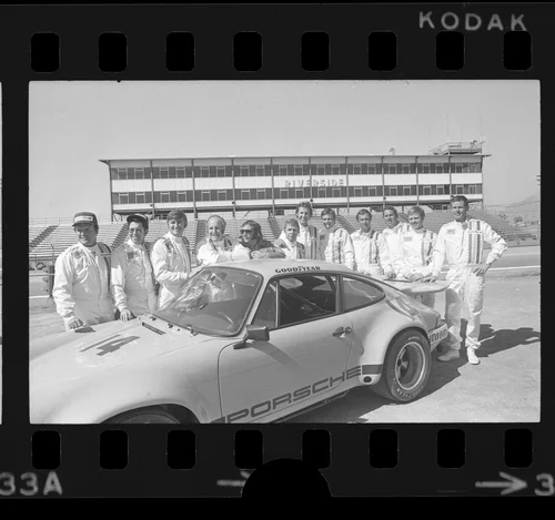 Group portrait of race car drivers around Porsche Carrera at Riverside International Raceway, Riverside, Calif., 1973