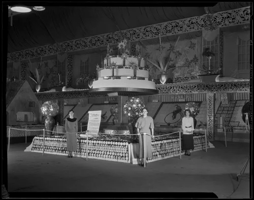 Three women stand in front of the Riverside display at the National Orange Show, San Bernardino, 1935