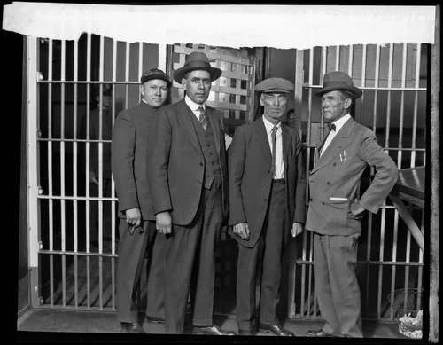 Jailer, Detective Paul Stevens, Cyrus G. Northcutt and Deputy Sheriff C. A. Quinn pose outside a jail cell, Riverside, 1928