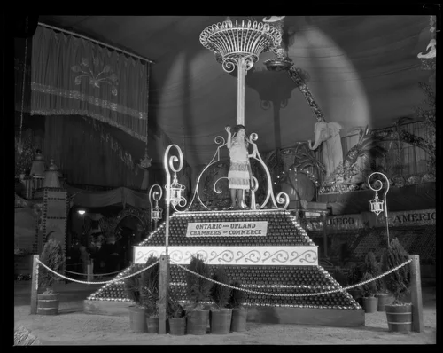 Woman stands upon the Ontario and Upland display at the National Orange Show, San Bernardino, 1926