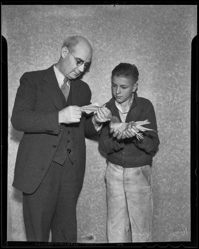Ernest W. Fischer Jr. holds a carrier pigeon while Mayor P. H. McQuillen reads a letter, Upland, 1936
