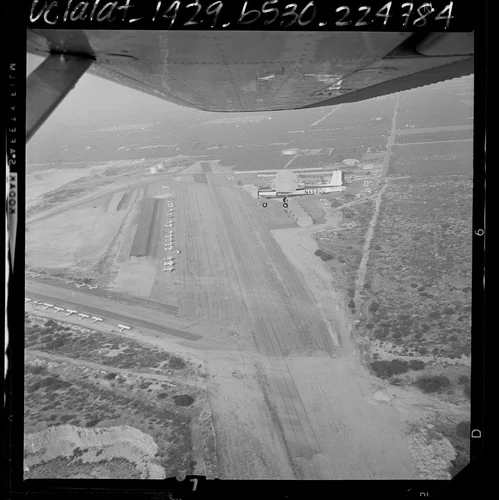 Aerial view of single engine plane above runway and surrounding terrain at Cable Airport in Upland, Calif., 1964