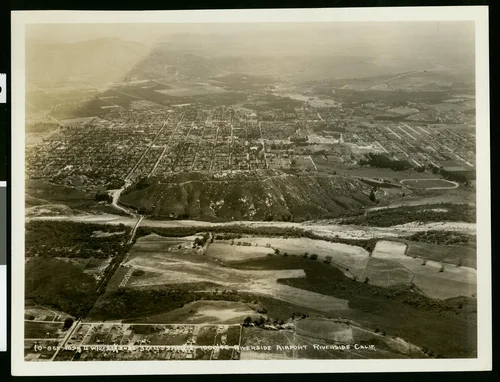 Aerial view of the Riverside Airport, showing a mountain ridge at center in front of a residential area, March 1932