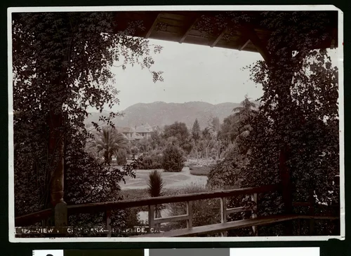 Exterior view of a Riverside residence, showing a city park in foreground, ca.1900
