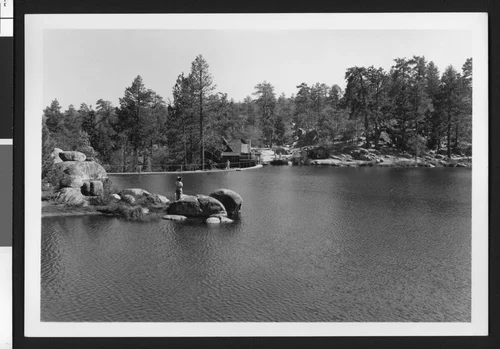 Man standing on boulders in Bartlett's Cedar Lake, ca.1950