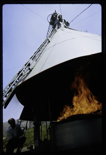 RESEARCH ASSOCIATE ERV MATEER OBSERVES THE BURNING OF WHEAT STRAW IN AGRICULTURAL BURNING TOWER; THE PURPOSE IS TO IMPROVE BURN METHODS OF AGRICULTURAL WASTE DISPOSAL, AND TO REDUCE CONTAMINANTS